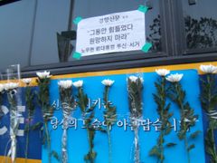길을 봉쇄하고 있는 경찰 버스에 붙여 있는 국화와 경향신문 호외