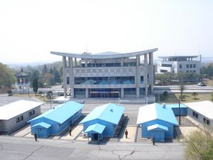 북한군이 판문점 공동 경비 구역 내 여러 청색 건물 사이를 지키고 있다. 뒤쪽에는 자유의 집이 보이고, 더 오른쪽 뒤에 평화의 집이 보인다.