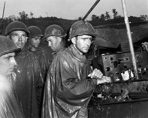 1945년 5월 8일, 미 제77보병사단 소속 미군 병사들이 유럽에서의 승전 소식을 라디오로 듣고 있다.