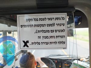 히브리어로 된 버스 운전기사 뒤에 게시된 승객 공지: "모든 승객은 원하는 좌석을 선택할 수 있습니다(장애인석 제외). 이와 관련하여 승객을 괴롭히는 것은 범죄가 될 수 있습니다".