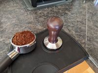 금속 바스켓에 탬퍼로 눌러 담는 모습