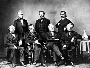 정장을 입은 일곱 명의 남성이 단체 사진을 찍고 있다.