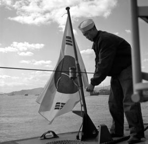 한국전쟁 중 미국으로부터 인수받은 후 대한민국 해군 병사가 어뢰정에 태극기를 게양하고 있다.