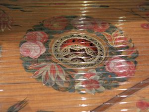 카를 콘라트 플라이셔가 1720년 함부르크에서 제작한 클라비코드의 세부 사항(바르셀로나 음악 박물관). 장식용 로제트가 현판 아래에 있으며, 현판 자체는 로제트 주변에 꽃 그림으로 장식되어 있다. 브리지는 오른쪽 아래에 있다.