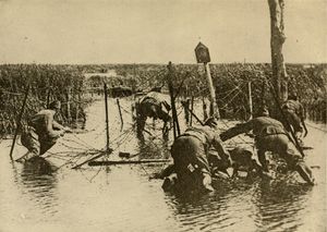 여러 겹으로 설치된 철조망 장애물을 통과하려는 미군 병사들.