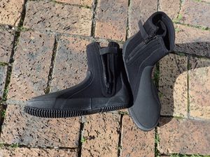 발가락과 뒤꿈치의 마모가 심한 부분에 단단한 밑창과 보강재가 있고, 지퍼 뒷면에 얇은 네오프렌 덧댐이 있어 누수를 줄이는 지퍼식 잠금장치가 있는 웨트슈트 부츠 한 켤레.