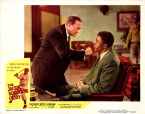 서 있는 백인 남성이 앉아 있는 흑인 남성의 턱 밑에서 주먹을 쥐고 있다. 흑인 야구 선수가 타석에 서 있는 사진이 삽입되어 있으며, "The Jackie Robinson Story"라는 자막이 겹쳐져 있다.