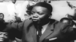 자신의 후원자들에 둘러싸인 촘베