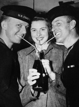 버그만과 두 명의 연합군 군인(왼쪽의 미국 해안경비대원과 영국 왕립 해군 소속 선원)이 뉴욕시의 스테이지 도어 캔틴에서 빨대 세 개를 이용해 음료를 마시고 있다. 이 캔틴에서는 연합군 군인들에게 담배, 샌드위치, 커피 등의 간식을 제공했다.