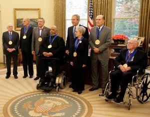 왼쪽부터 레너드 가먼트, 루이스 오친클로스, 파키토 드리베라, 제임스 드프리스트, 티나 라미레즈, 로버트 드 니로, 올리 존스턴. 조지 W. 부시 대통령이 2005년 미국 예술훈장 수상자들과 함께 서 있다.