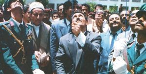 알리 압둘라 살레가 예멘 국기를 게양하고 있으며, 그 뒤에 알리 살렘 알 베이흐가 있다.