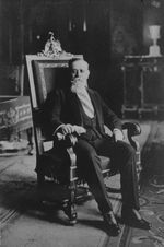 대통령 띠를 두르고 대통령 의자에 앉아 있는 카란사