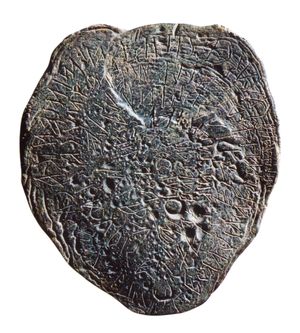 대조를 높이기 위해 측면에서 조명된 모호한 원형 판. 문자는 윤곽선을 따라 휘어져 있습니다.