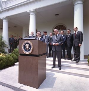 데이비드 록펠러가 1964년 6월 15일 백악관 장미정원에서 린든 존슨 대통령을 비롯한 여러 사람들이 지켜보는 가운데 국제경영자봉사단(IESC) 발족을 발표하는 사진.