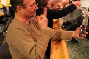 한 남자가 왼손에 스마트폰을 들고 수화를 하고 있다.