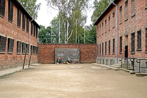 사형 집행장 "죽음의 벽"과 아우슈비츠 수용소 정치범 유니폼(빨간색 삼각형이 있는 파란색과 흰색 줄무늬)