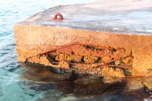 콘크리트가 떨어져 나가면서 안에 있던 철근이 물과 접촉하여 녹이 슨 모습.