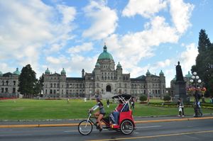 브리티시컬럼비아주 의사당 건물을 지나 자전거를 타고 가는 사람들