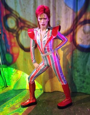 A wax figure of a red-haired man with a gold "astral sphere" across his forehead.