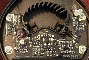 덮개를 제거한 광학식 연기 감지기. 상단에 걸쳐 아치형으로 된 각진 플라스틱은 차광판이다.