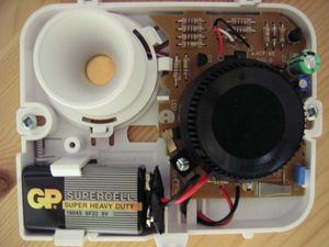 기본 이온화 연기 감지기 내부. 오른쪽의 검은색 원형 구조는 이온화 챔버이다. 왼쪽 상단의 흰색 원형 구조는 경보음을 생성하는 압전 혼이다.