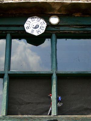 삼각형 프레임 안의 태극도와 액막이 거울. 이 부적들은 악령을 쫓고 불운으로부터 집을 보호한다고 믿어진다.