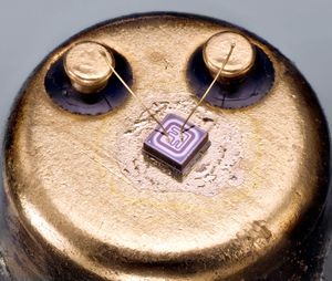 2N2222 NPN 트랜지스터의 다이: NPN 재료는 컬렉터가 바닥에 있는 층으로 만들어진다. 본딩 와이어는 왼쪽 리드에 베이스의 금속화를, 오른쪽 리드에 에미터를 연결한다. 컬렉터는 세 번째 외부 리드를 사용하여 캔에 연결된다.