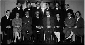 monochrome photograph of eight seated people, with a row of six people standing behind them