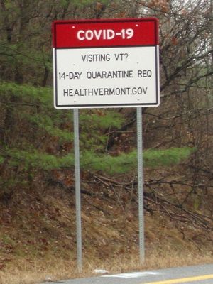 2020년 11월에 촬영된, 버몬트주의 주간 고속도로 91호선 출구에 있는 도로 표지판으로, COVID-19에 대응하여 채택된 검역 정책에 대해 주에 입국하는 사람들에게 알리고 있다
