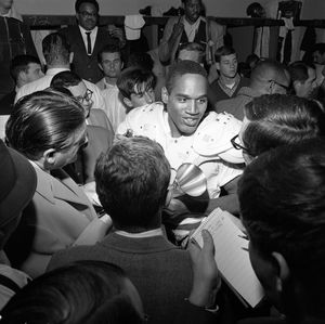 Simpson surrounded by reporters, smiling