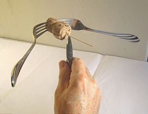 포크, 코르크, 이쑤시개의 전체 질량중심은 펜 끝 위에 있다.