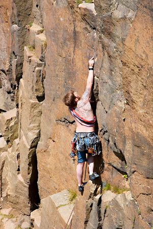 선등자가 전통 등반 루트를 오르며, 보호 장비로 사용할 너트를 바위틈에 설치하고 있다.