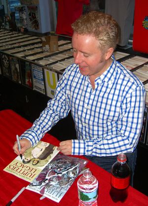 마크 밀러(Mark Millar) 작가가 프랭크 콰이틀리(Frank Quitely)와 브라이언 히치(Bryan Hitch) 표지의 주피터스 레거시 1권에 사인하는 모습 (맨해튼 미드타운 코믹스(Midtown Comics)에서)