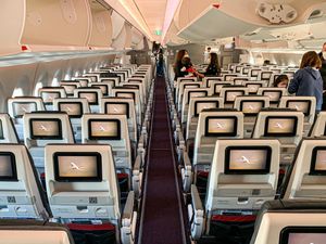 좌석 뒤쪽에 TV가 있고 천장에는 짐칸이 있는 항공기 이코노미석 내부