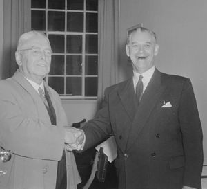 홀리오크(오른쪽)가 1957년 선거에서 노동당의 승리를 거둔 월터 내시에게 축하를 건네는 모습