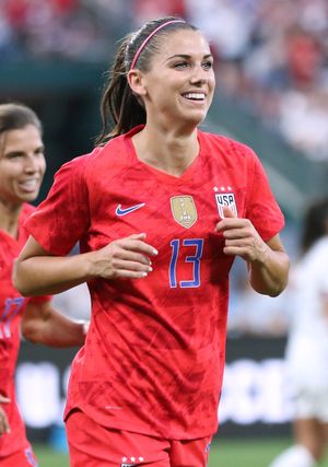 축구선수 알렉스 모건(Alex Morgan)의 사진. 13번이 새겨진 붉은색 미국 유니폼을 입고 조깅을 하고 있다.