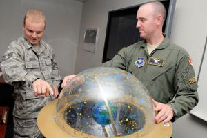 천구의를 사용하여 학생에게 별들 사이를 지나는 태양의 겉보기 경로를 보여주는 교관