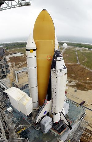 발사대에 수직으로 서 있는 우주왕복선 조립체, 외부 연료탱크에 빨간 원이 표시됨