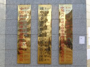 중국어(표의문자), 이(음절 문자), 그리고 하니어(알파벳 하니어 병음 로마자 표기)로 된 삼개국어 표지판. 리하오자이향 정부 청사, 운남성 젠수이현. 이어와 하니어 텍스트는 중국어 텍스트와 음절 대 음절로 대응되는 것으로 보인다.