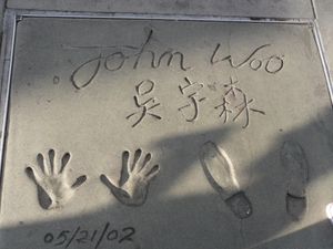 할리우드 그로만스 차이니스 극장 앞에 새겨진 오우삼 감독의 손자국과 발자국. 상단에는 "John Woo", 중앙에는 중국어 이름 "吳宇森", 하단에는 "5/21/2002"가 적혀 있다.