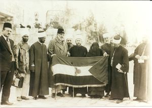 인도 독립 운동가 샤우카트 알리가 1931년 예루살렘(Jerusalem)에서 아민 알 후세이니(Amin al-Husseini)와 다른 팔레스타인 아랍 민족주의자들로부터 (중앙에 돔 오브 더 록이 그려진) 팔레스타인 아랍 깃발을 받는 모습