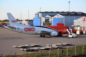 TNT 항공 보잉 737-300F 항공기가 화물 터미널에 있으며, 배경에는 DHL 항공 A300-600F 항공기가 있다.