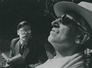 정원에서 나이든 맹인 남성에게 젊은 안경 쓴 백인 남성이 글을 읽어주는 모습