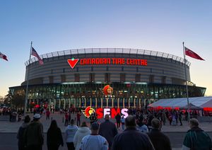 People milling about a large brick color building with large sign Canadian Tire Centre