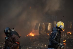 2014년 2월 18일 키이우, 시위대가 타이어 연기 속에서 저격수의 공격을 피하며 진압 경찰에게 벽돌을 던지는 모습