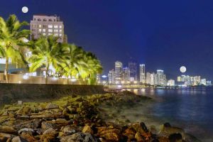 이 시뮬레이션된 스카이라인에서 달은 멀리 있는 건물 근처에서 가까이 있는 건물 근처보다 더 크게 보입니다.