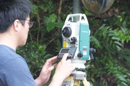 섬의 도로에서 탑콘(Topcon)사의 전자식 시도라이트(소키아(Sokkia)·논프리즘 토탈스테이션 Series50RX 2010)를 사용하여 측량하는 모습(가케로마섬)