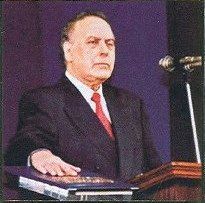 알리예프가 단상에서 책 위에 손을 올리고 서 있는 모습