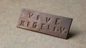 키겔리 5세 만세("Vive Kigeli V")라는 슬로건이 새겨진 왕당파 핀 배지로, 르완다 혁명 당시의 것이다