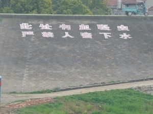 중국 후베이성 홍호시의 양쯔강 제방에 칠해진 경고: "주혈흡충이 여기 있다. 사람과 가축은 물에 들어가는 것이 엄격히 금지되어 있습니다!"